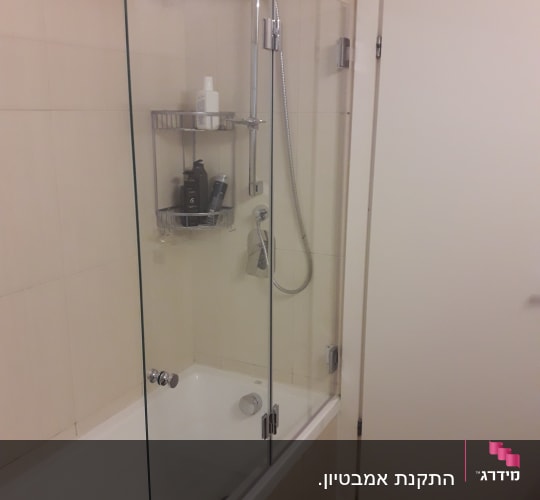 מקלחת עם דלת זכוכית ומדף מוצרים